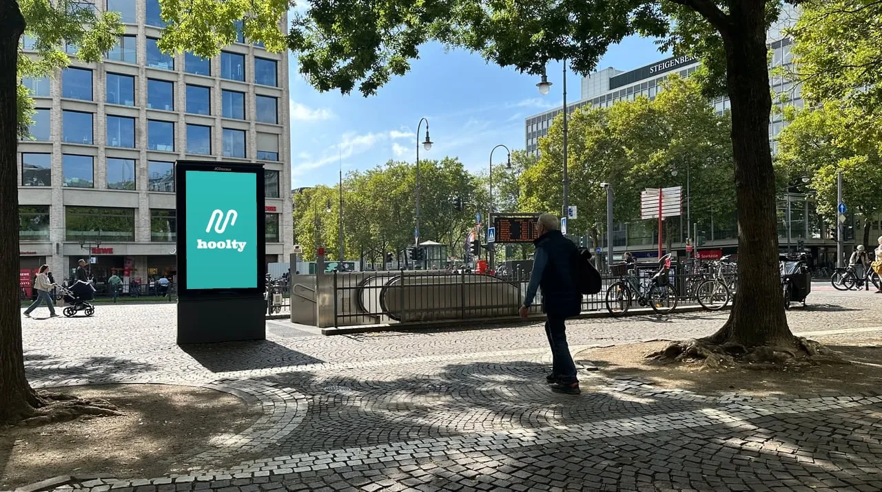 Hoolty-advertentie op een digitaal stadsscherm naast een metro-ingang